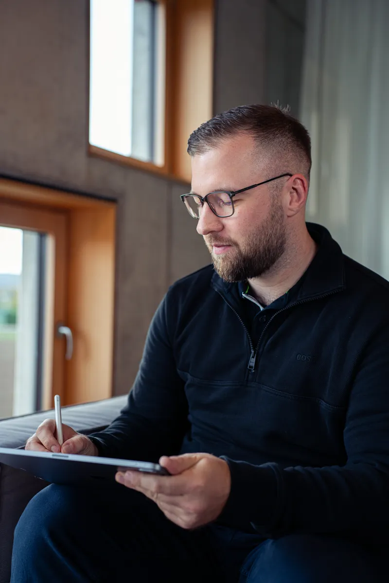 Marvin Jennrich sitzt am Fenster und macht mit einem Stift Notizen auf dem Tablet