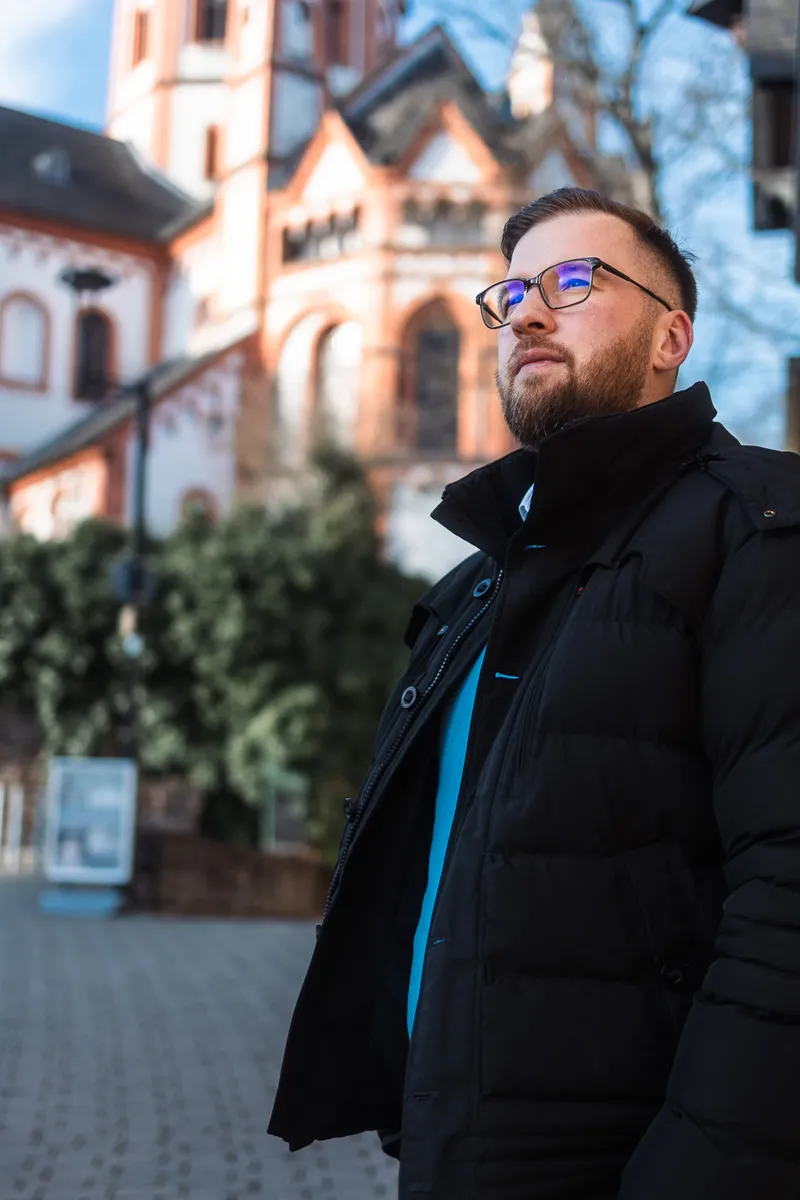 Marvin Jennrich in Winterjacke vor einer Kirche in der Altstadt